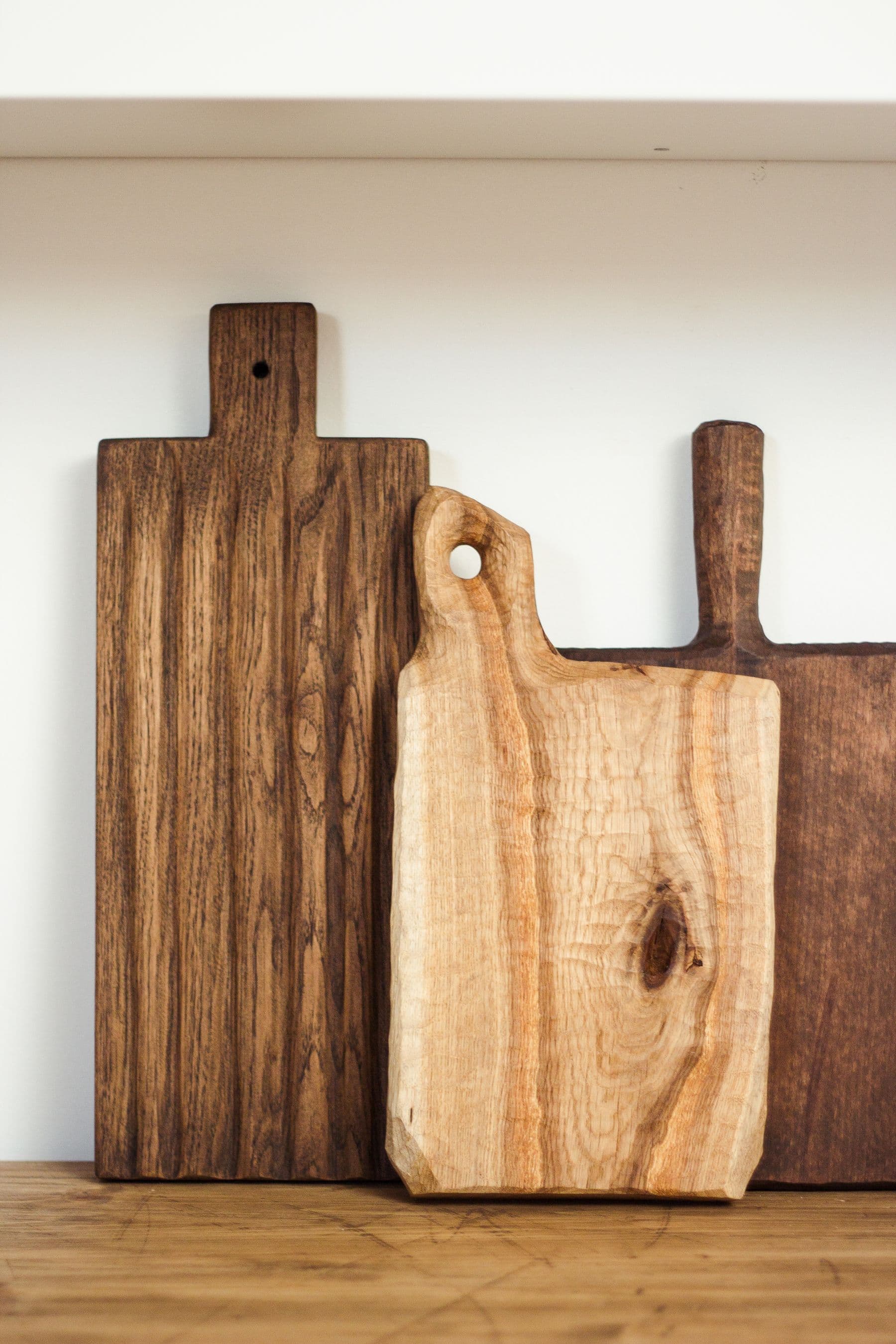 A group of wood serving boards arranged against a light wall